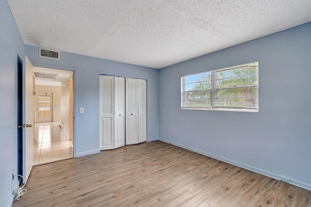 393 Fanshaw J, Boca Raton, FL 33434 - unfurnished bedroom with light wood finished floors, a textured ceiling, baseboards, and a closet
