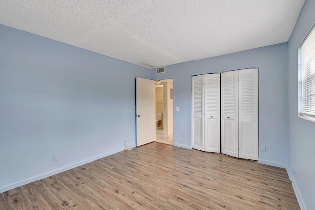 393 Fanshaw J, Boca Raton, FL 33434 - unfurnished bedroom featuring light wood-style floors, baseboards, a textured ceiling, and a closet