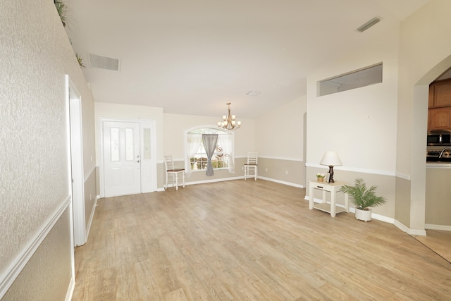 1985 SW Glenco St, Port Saint Lucie, FL 34953 - unfurnished living room featuring light wood-type flooring, a chandelier, arched walkways, and baseboards