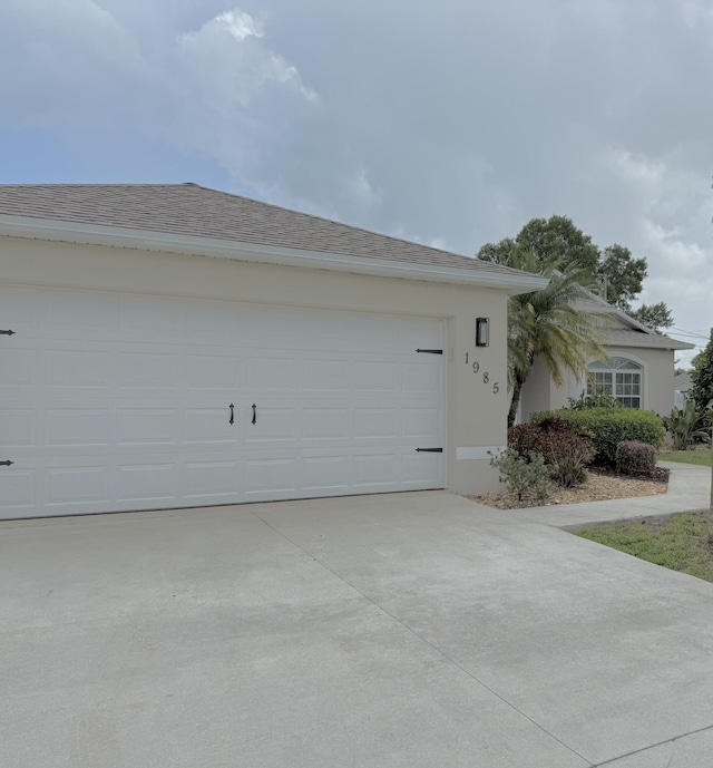 1985 SW Glenco St, Port Saint Lucie, FL 34953 - view of front of home featuring concrete driveway, stucco siding, a garage, and a shingled roof