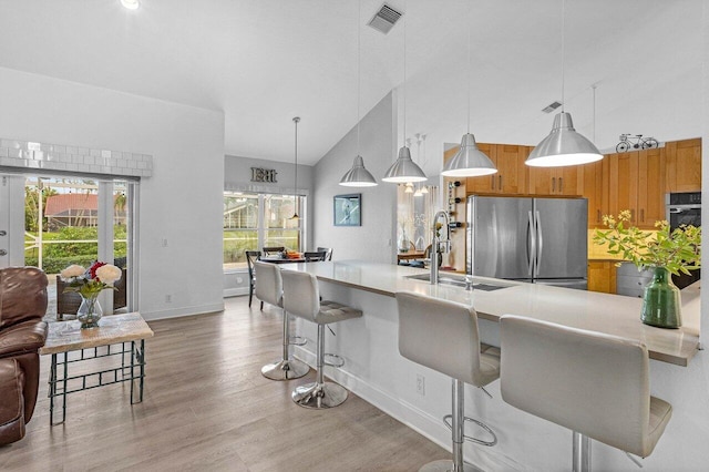 9391 Aqua Vista Blvd, Boynton Beach, FL 33437 - kitchen featuring stainless steel appliances, high vaulted ceiling, brown cabinetry, light countertops, and light wood-style floors