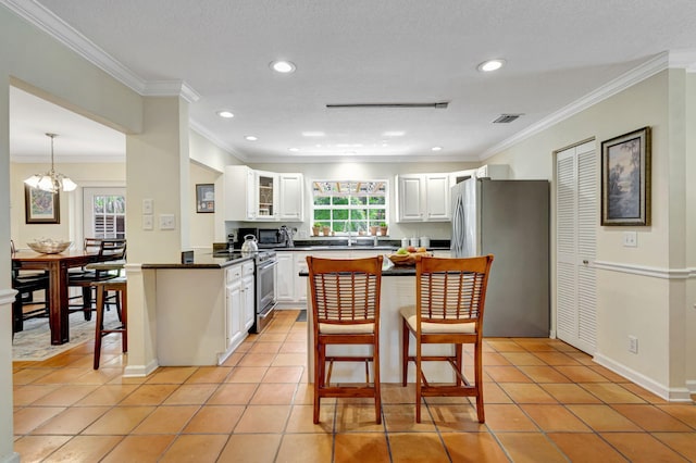 16095 121st Ter N, Jupiter, FL 33478 - kitchen featuring appliances with stainless steel finishes, a kitchen breakfast bar, white cabinetry, dark countertops, and ornamental molding