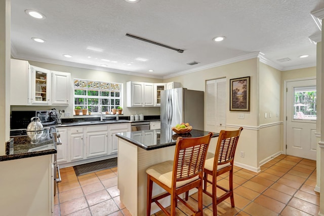 16095 121st Ter N, Jupiter, FL 33478 - kitchen featuring appliances with stainless steel finishes, healthy amount of natural light, light tile patterned floors, a breakfast bar, and recessed lighting