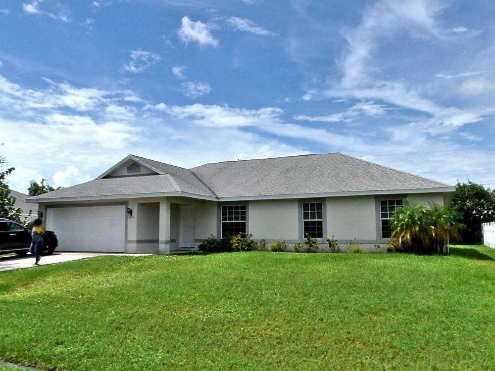 4286 SW Carl St, Port Saint Lucie, FL 34953 - single story home featuring stucco siding, an attached garage, a front yard, driveway, and roof with shingles
