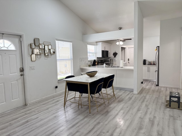 1518 Royal Forest Ct, Palm Springs, FL 33406 - dining room featuring light wood-style floors, a ceiling fan, high vaulted ceiling, baseboards, and a chandelier