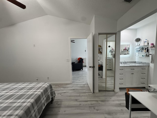 1518 Royal Forest Ct, Palm Springs, FL 33406 - bedroom with light wood finished floors, vaulted ceiling, a sink, and a textured ceiling