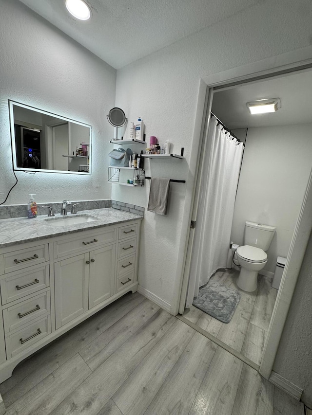 1518 Royal Forest Ct, Palm Springs, FL 33406 - full bath with wood finished floors, toilet, vanity, a textured wall, and baseboards