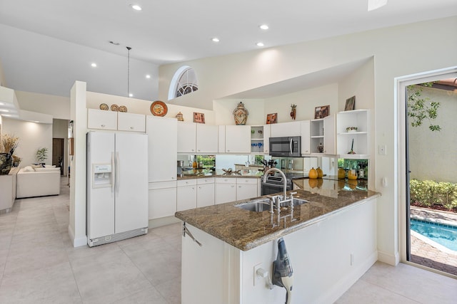 23193 Via Stel, Boca Raton, FL 33433 - kitchen with white refrigerator with ice dispenser, stainless steel microwave, open shelves, a peninsula, and white cabinetry