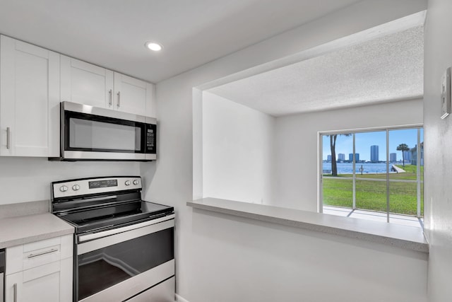 2936 Lake Shore Dr Unit 108, Riviera Beach, FL 33404 - kitchen featuring stainless steel appliances, white cabinetry, light countertops, a water view, and recessed lighting