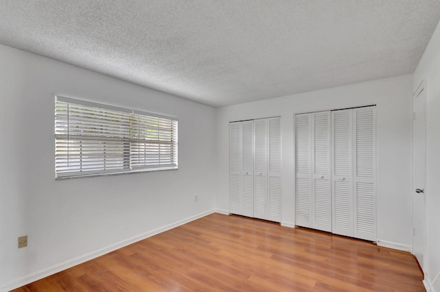 2936 Lake Shore Dr Unit 108, Riviera Beach, FL 33404 - unfurnished bedroom with multiple closets, wood finished floors, and a textured ceiling