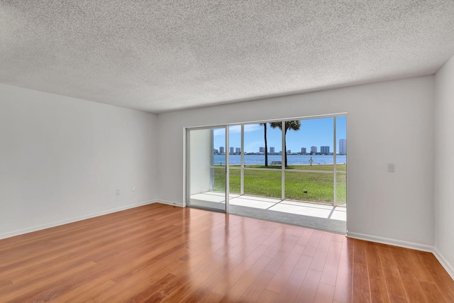 2936 Lake Shore Dr Unit 108, Riviera Beach, FL 33404 - unfurnished room featuring a water view, wood finished floors, and a textured ceiling