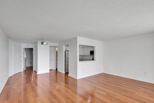 2936 Lake Shore Dr Unit 108, Riviera Beach, FL 33404 - unfurnished living room with a textured ceiling, wood finished floors, and ceiling fan