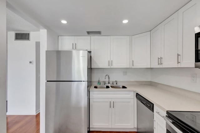 2936 Lake Shore Dr Unit 108, Riviera Beach, FL 33404 - kitchen with stainless steel appliances, white cabinetry, light countertops, light wood-style flooring, and recessed lighting