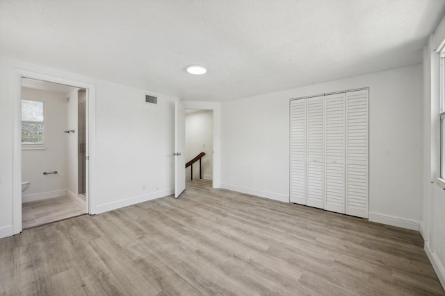 811 Hunter St, West Palm Beach, FL 33405 - unfurnished bedroom with light wood-style flooring, baseboards, a closet, and connected bathroom