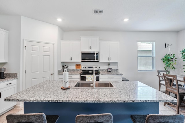 2431 Crowned Eagle Cir SW, Vero Beach, FL 32962 - kitchen featuring appliances with stainless steel finishes, a kitchen bar, light tile patterned floors, a sink, and light stone countertops