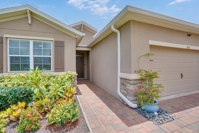 2431 Crowned Eagle Cir SW, Vero Beach, FL 32962 - view of exterior entry with stucco siding, an attached garage, and stone siding