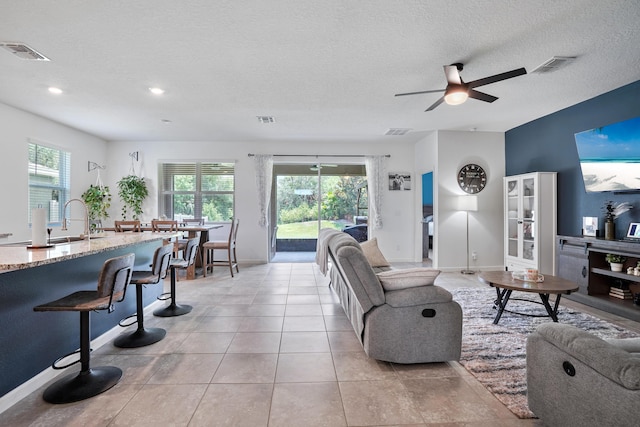 2431 Crowned Eagle Cir SW, Vero Beach, FL 32962 - living room with a ceiling fan, a textured ceiling, baseboards, and light tile patterned floors