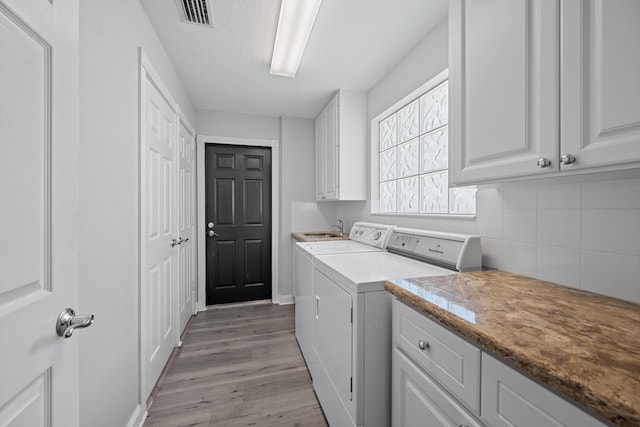 10834 SW Dardanelle Dr, Port Saint Lucie, FL 34987 - washroom featuring separate washer and dryer, cabinet space, light wood-type flooring, and baseboards