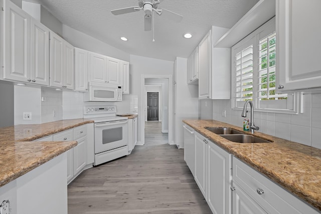 10834 SW Dardanelle Dr, Port Saint Lucie, FL 34987 - kitchen with white appliances, a sink, white cabinets, light wood-type flooring, and recessed lighting