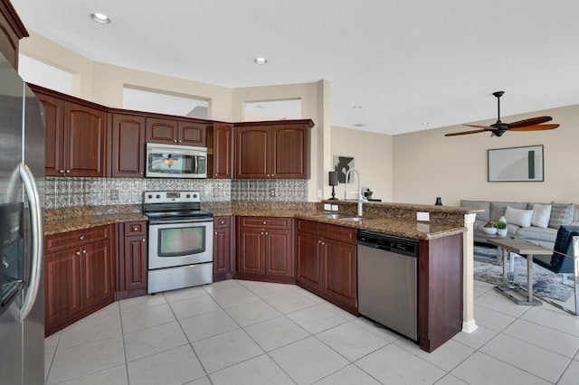 3559 Hudson Ln, Boynton Beach, FL 33436 - kitchen featuring stainless steel appliances, a peninsula, open floor plan, decorative backsplash, and dark stone countertops