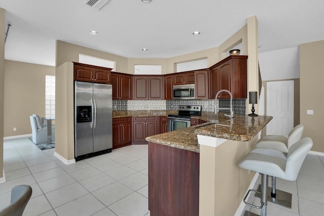 3559 Hudson Ln, Boynton Beach, FL 33436 - kitchen with stainless steel appliances, a peninsula, backsplash, dark stone counters, and recessed lighting