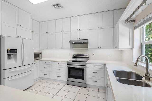 6321 Lansdowne Cir, Boynton Beach, FL 33472 - kitchen with appliances with stainless steel finishes, a sink, under cabinet range hood, white cabinets, and tasteful backsplash