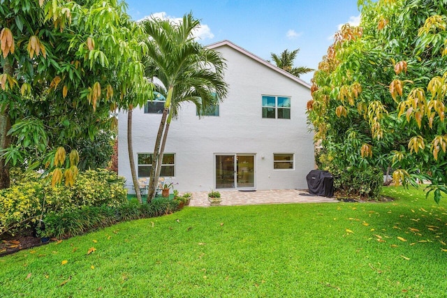 6321 Lansdowne Cir, Boynton Beach, FL 33472 - rear view of house featuring stucco siding, a patio, and a lawn