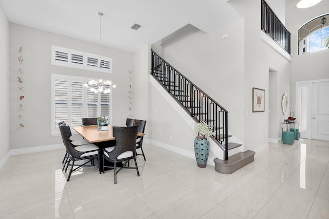 9350 Eden Roc Ct, Delray Beach, FL 33446 - dining space with a towering ceiling, a chandelier, stairway, baseboards, and tile patterned floors