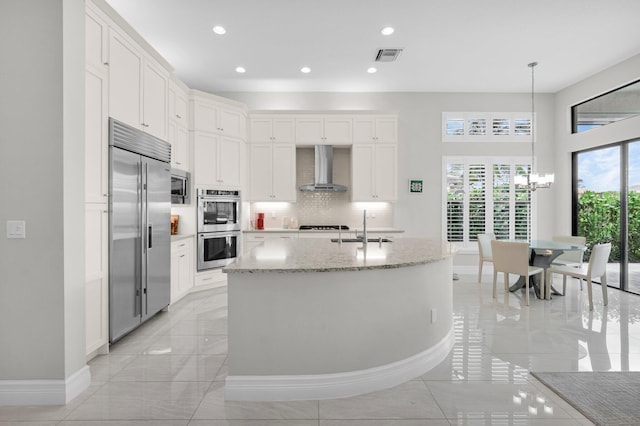 9350 Eden Roc Ct, Delray Beach, FL 33446 - kitchen with built in appliances, wall chimney range hood, baseboards, a sink, and white cabinetry