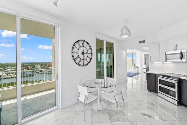 3700 S Ocean Blvd Unit 1210, Highland Beach, FL 33487 - dining area with light marble finish floors, a water view, and baseboards