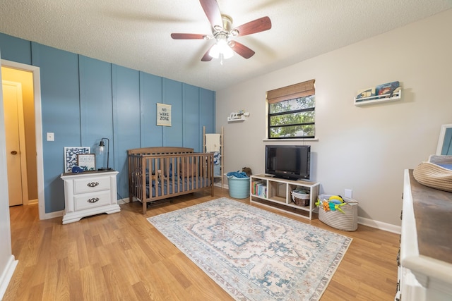 1793 SW 22nd Ter, Okeechobee, FL 34974 - bedroom featuring wood finished floors, a crib, ceiling fan, a textured ceiling, and baseboards