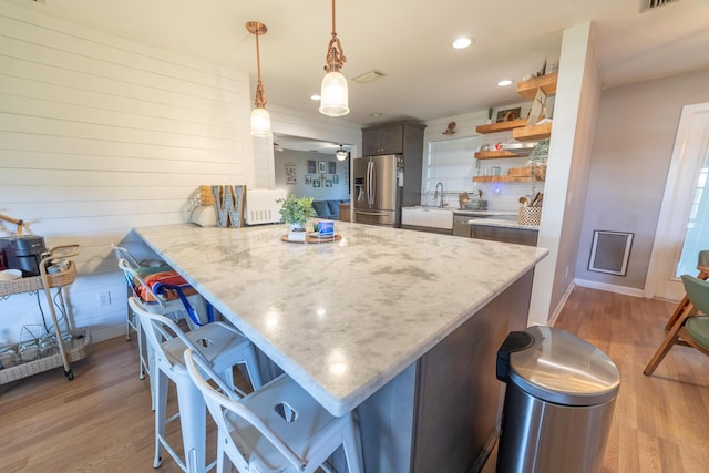 1793 SW 22nd Ter, Okeechobee, FL 34974 - kitchen with stainless steel fridge, open shelves, a breakfast bar, light wood-style floors, and a peninsula