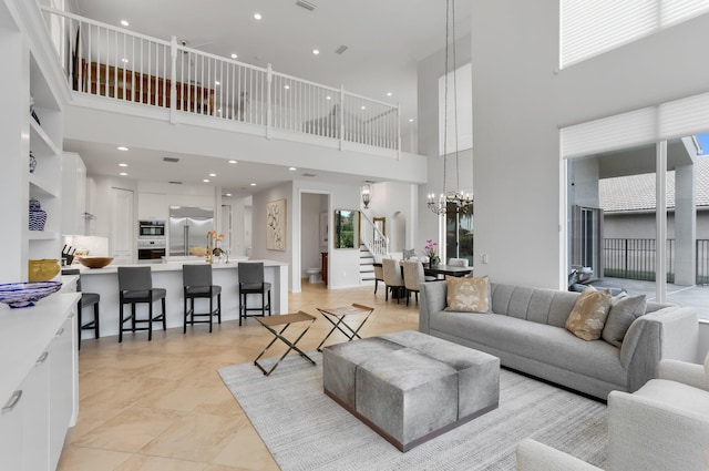 6636 Dana Point Cv, Delray Beach, FL 33446 - living area with a towering ceiling, a chandelier, stairway, healthy amount of natural light, and light tile patterned flooring