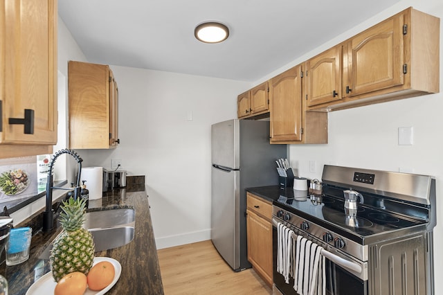 2137 Longwood Rd, West Palm Beach, FL 33409 - kitchen featuring stainless steel appliances, a sink, light wood finished floors, baseboards, and dark stone counters