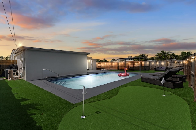 2137 Longwood Rd, West Palm Beach, FL 33409 - pool at dusk featuring a putting area and a fenced backyard