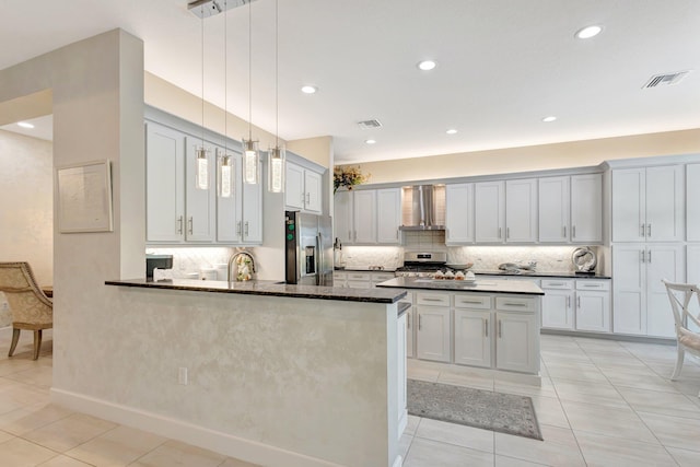 11051 SW Ivory Springs Ln, Port Saint Lucie, FL 34987 - kitchen featuring stainless steel appliances, wall chimney exhaust hood, light tile patterned flooring, backsplash, and a peninsula