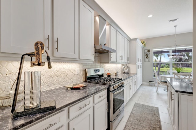 11051 SW Ivory Springs Ln, Port Saint Lucie, FL 34987 - kitchen with stainless steel gas range oven, wall chimney exhaust hood, backsplash, light tile patterned floors, and dark stone counters