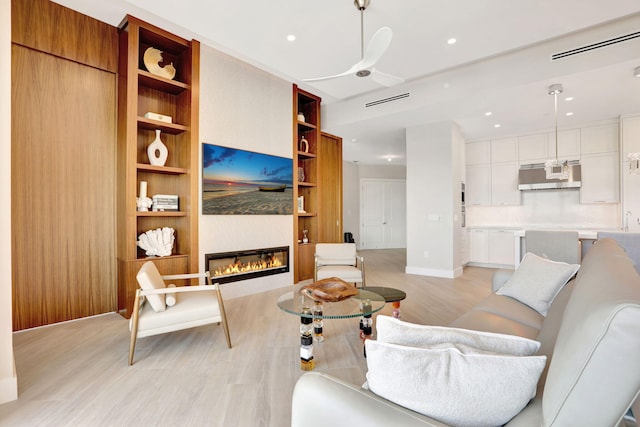 1 N Ocean Blvd Unit Ph05, Pompano Beach, FL 33062 - living room featuring light wood-type flooring, built in shelves, a fireplace, a ceiling fan, and baseboards