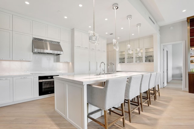 1 N Ocean Blvd Unit Ph05, Pompano Beach, FL 33062 - kitchen featuring oven, exhaust hood, light wood-style floors, a spacious island, and light countertops