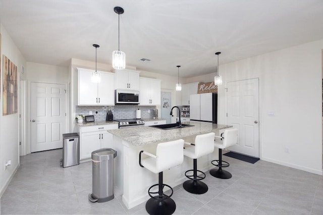 12314 SW Rimini Way, Port Saint Lucie, FL 34987 - kitchen with white appliances, a sink, decorative backsplash, baseboards, and an island with sink