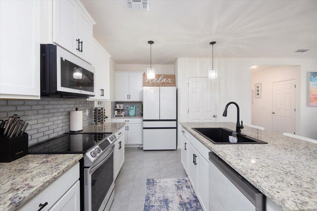 12314 SW Rimini Way, Port Saint Lucie, FL 34987 - kitchen with stainless steel appliances, a sink, tasteful backsplash, white cabinets, and pendant lighting
