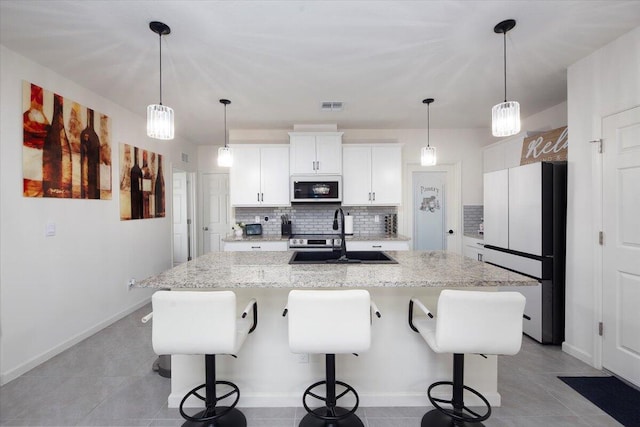 12314 SW Rimini Way, Port Saint Lucie, FL 34987 - kitchen with freestanding refrigerator, a sink, backsplash, a kitchen island with sink, and white cabinetry