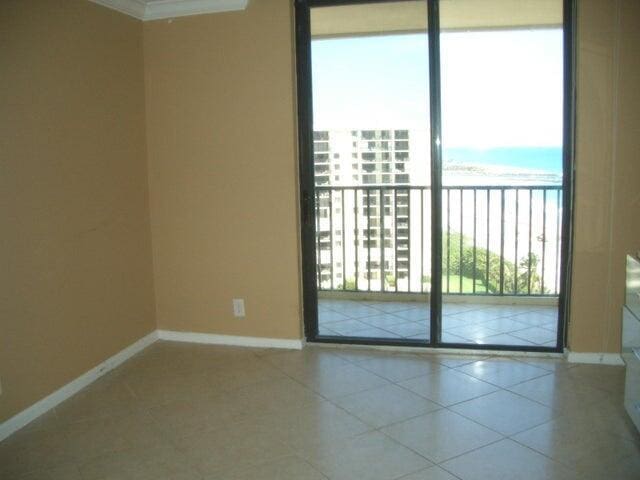 300 Ocean Trail Way Unit 1302, Jupiter, FL 33477 - spare room featuring baseboards, tile patterned floors, view of water and beach, and crown molding