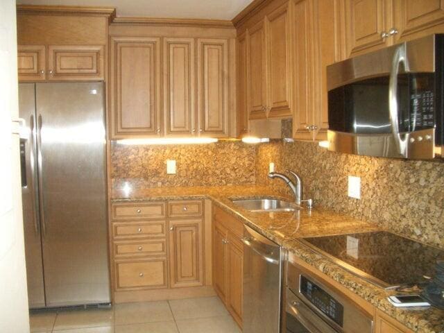 300 Ocean Trail Way Unit 1302, Jupiter, FL 33477 - kitchen with appliances with stainless steel finishes, a sink, light tile patterned floors, light stone counters, and backsplash