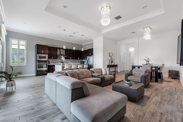 8762 SW Montova Way, Port Saint Lucie, FL 34987 - living area with a raised ceiling, light wood-style floors, a chandelier, baseboards, and ornamental molding