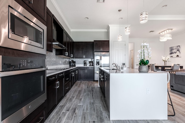 8762 SW Montova Way, Port Saint Lucie, FL 34987 - kitchen with appliances with stainless steel finishes, crown molding, backsplash, a sink, and decorative light fixtures