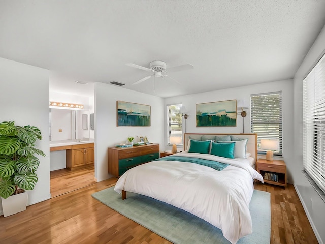 3961 SW Greenwood Way Unit D, Palm City, FL 34990 - bedroom featuring light wood-style flooring, multiple windows, ceiling fan, and ensuite bathroom