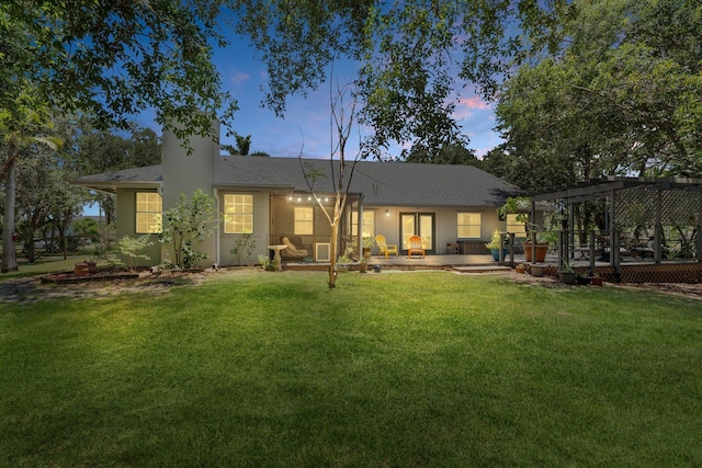 16673 75th Way N, Palm Beach Gardens, FL 33418 - back of house at dusk with a pergola, a lawn, a chimney, and a shingled roof