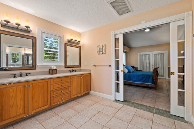 16673 75th Way N, Palm Beach Gardens, FL 33418 - bathroom with double vanity, french doors, ensuite bathroom, a textured ceiling, and tile patterned flooring