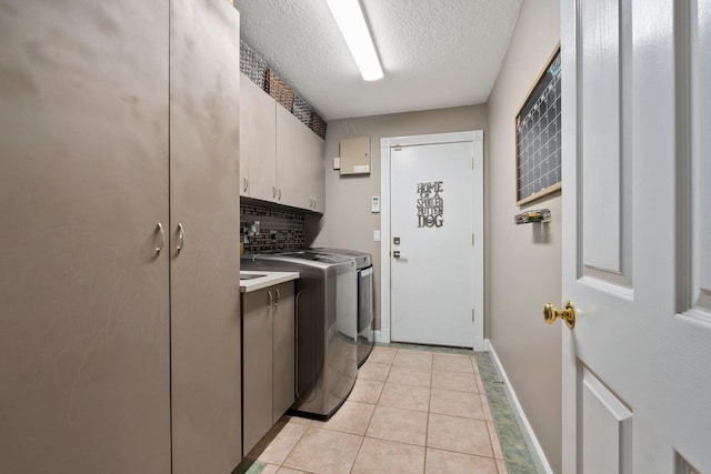 16673 75th Way N, Palm Beach Gardens, FL 33418 - laundry area with cabinet space, washer and clothes dryer, a textured ceiling, baseboards, and light tile patterned flooring